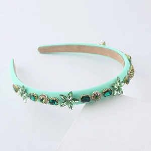 Mint green headband with sparkling rhinestones and pearls on a geometric display