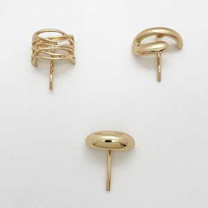 Detail of three golden metal ponytail hooks in minimalist twisted and smooth designs