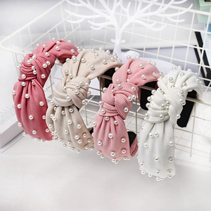 Detail of knotted headbands with pearl accents in pink, beige, and white textured fabric