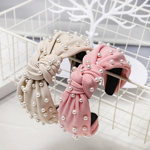Close-up of textured knit knot headbands with faux pearl details in beige and pink
