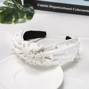 Macro view of a white knotted headband with pearl embellishments and textured fabric
