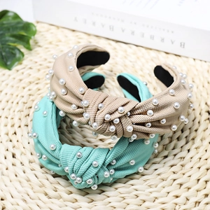 Detail of fabric knotted headbands with pearl accents in beige and mint green colors