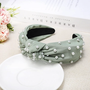 Detail of light green knitted headband with pearl embellishments and twist knot design