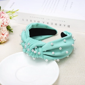 Detailed view of mint green knotted headband with faux pearls and textured woven fabric