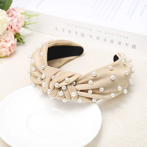 Elegant apricot knotted fabric headband with white pearl accents on ceramic tray