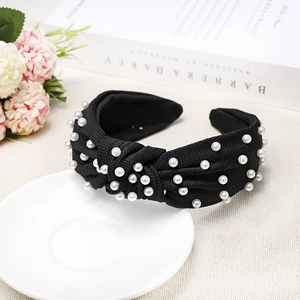 Detail of black knotted headband with white pearls on ribbed fabric and elegant setting