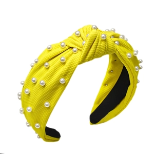Yellow knotted headband with white pearls and ribbed knit fabric on a white background