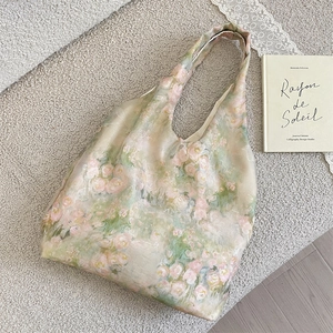Dettaglio elegante borsa in raso con rose rosa su una superficie di tessuto morbido