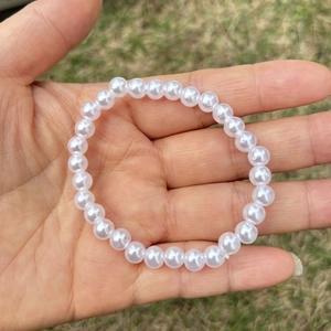 Close-up of white imitation pearl bracelet on palm with blurred outdoor background
