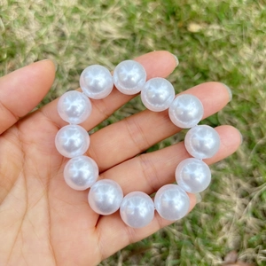 Close-up of a child's white faux pearl bracelet with large beads on elastic cord