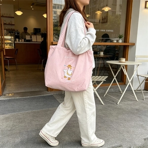 Detail of pink canvas tote bag featuring cute cartoon goose embroidery and drawstring closure