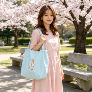 Detailed view of light blue canvas tote bag featuring cute cartoon duck embroidery and drawstring