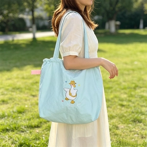 Detail of light blue tote bag featuring cute duck embroidery and drawstring closure