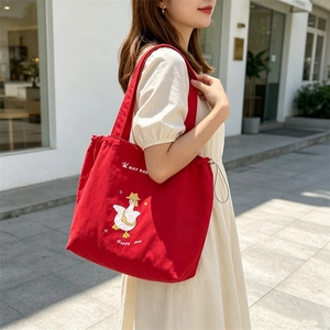 Detail of red canvas tote bag featuring a cute duck embroidery and drawstring closure