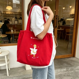 Detail of red canvas tote bag with white duck embroidery and drawstring closure