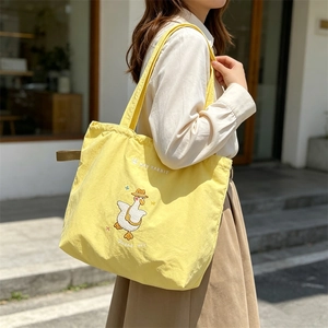 Close-up of cute cartoon goose embroidery on a bright yellow canvas tote bag