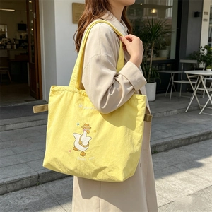 Detail of yellow canvas tote bag with cute cartoon duck embroidery and drawstring closure