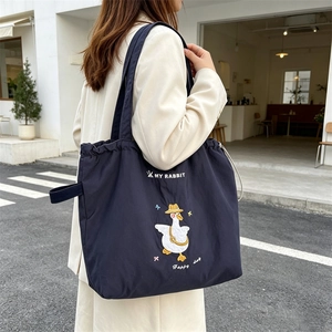 Detail of navy canvas tote featuring cartoon goose embroidery and drawstring closure