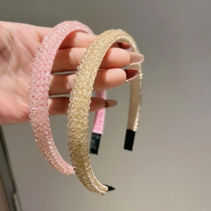 Handheld view of dual four-row crystal headbands in pink and champagne gold finishes