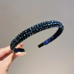 Detail of multi-layered deep blue crystal beads on a non-slip hairband held by hand