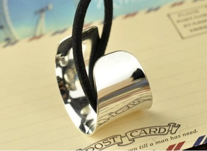 Macro detail of a silver polished metal hair tie with a black elastic band on a postcard