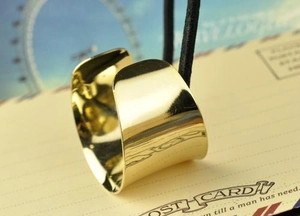 Macro shot of polished gold curved metal accessory tied with black string on a vintage card