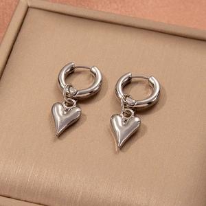 Detailed close-up of silver heart dangle earrings with polished stainless steel finish