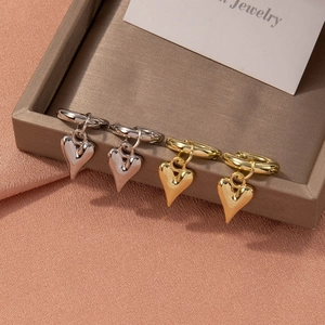 Detailed view of polished heart pendant hoop earrings in gold and silver finishes