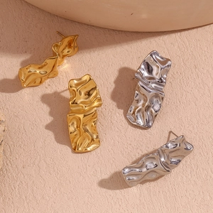 Détails macro des boucles d'oreilles texturées en finitions or 18K et argent