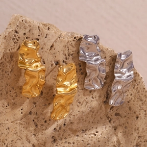 Détail de boucles d'oreilles plissées irrégulières en or 18 carats et argent sur pierre