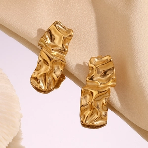 Vue macro de boucles d'oreilles dorées 18K à texture froissée en métal liquide