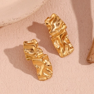 Gros plan sur les boucles d'oreilles en acier doré 18K avec une texture plissée unique