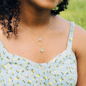 Double-layered gold gemstone necklace with pink heart and green leaf oval pendants