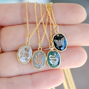 Handheld display of four oval enamel pendants with snake butterfly and flower patterns