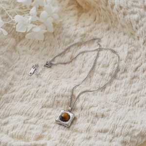 French vintage stainless steel necklace with geometric tiger eye stone on knit background