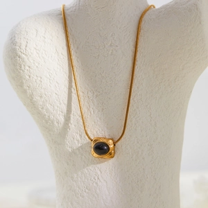 Macro shot of gold snake chain with geometric black onyx pendant on display