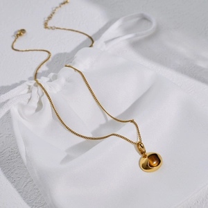 Detailed view of gold stainless steel necklace with round brown tiger eye stone pendant