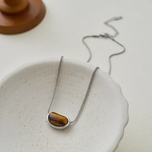 Macro detail of natural tiger eye stone pendant on a silver stainless steel chain