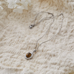 Macro shot of silver geometric pendant with natural tiger eye stone on a soft knit background