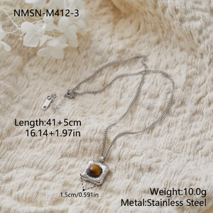 Détail macro du collier géométrique en acier inoxydable avec oeil de tigre sur tricot