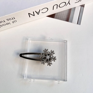 Barrette à cheveux flocon de neige avec strass et perle sur fond blanc texturé