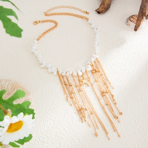 Detail of gold starfish necklace with white sea stone tassels on white sand background