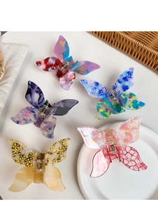 Detail view of five assorted acetate butterfly hair claws in retro colors and patterns