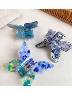 Detailed view of three butterfly hair claws in diverse marble and floral acetate patterns