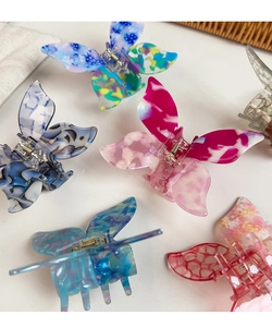 Flat lay of colorful butterfly hair claws with marble acetate texture and metal springs