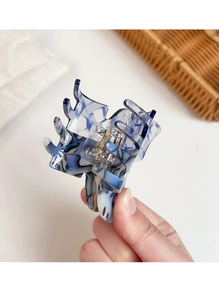 Detail view of butterfly hair claw clip with marble texture and golden metal spring