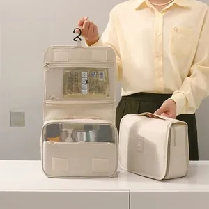 Hanging beige toiletry bag with multiple zipper compartments and folding design