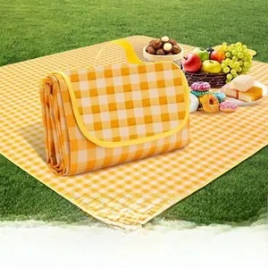 Waterproof yellow checkered picnic blanket folded and laid on grass with snacks