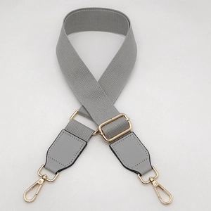 Detail view of light grey adjustable canvas strap with gold lobster clasps and metal buckle
