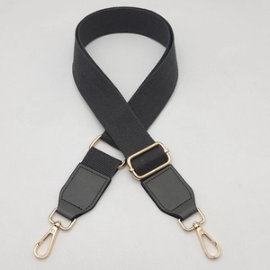 Detail of adjustable black canvas strap with golden swivel clasps and metal buckle